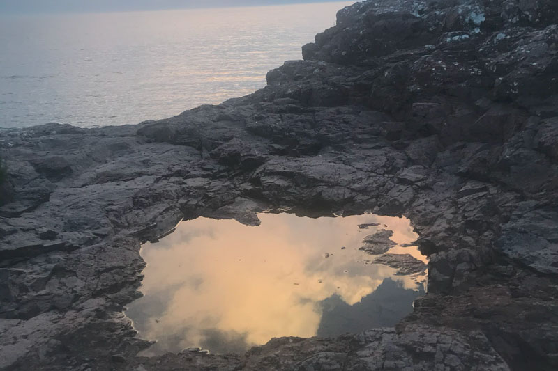 image of the sky reflected in a puddle within a pot hole